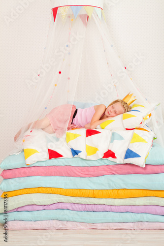 little girl lying on a pile of mattresses