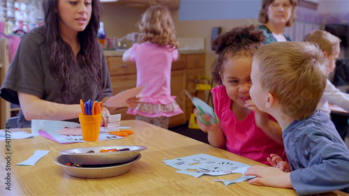 Two cute school children work on a project at a table together during art class