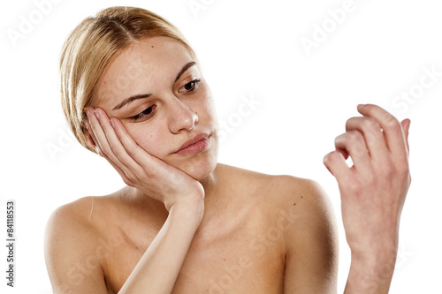 dissatisfied young woman looking at her nails