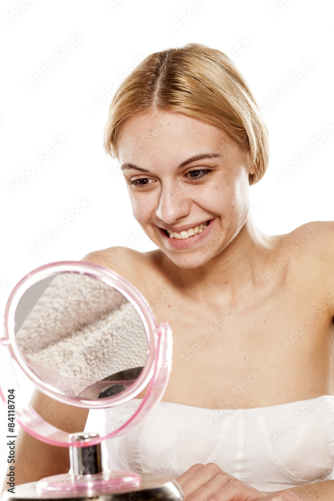 Beautiful young woman looking at her smile in the mirror Beautiful young woman looking at her smile in the mirror
