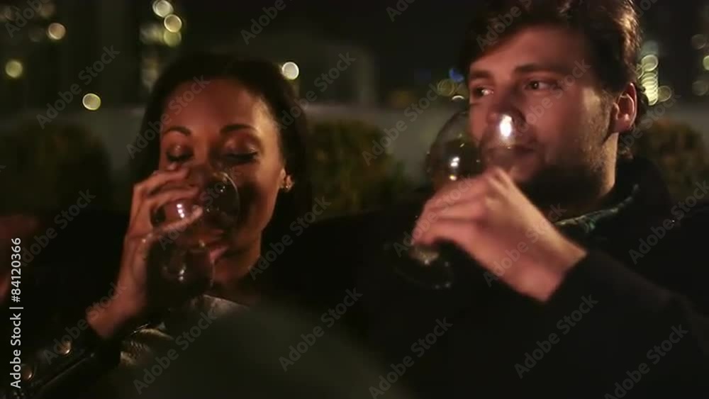 A couple sits next to a fire and looks at a phone together with drinks A couple sits next to a fire and looks at a phone together with drinks