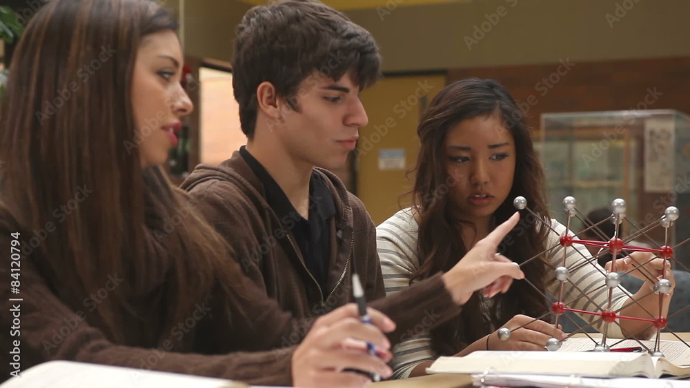 College students study course material in a group at a table filled with books College students study course material in a group at a table filled with books