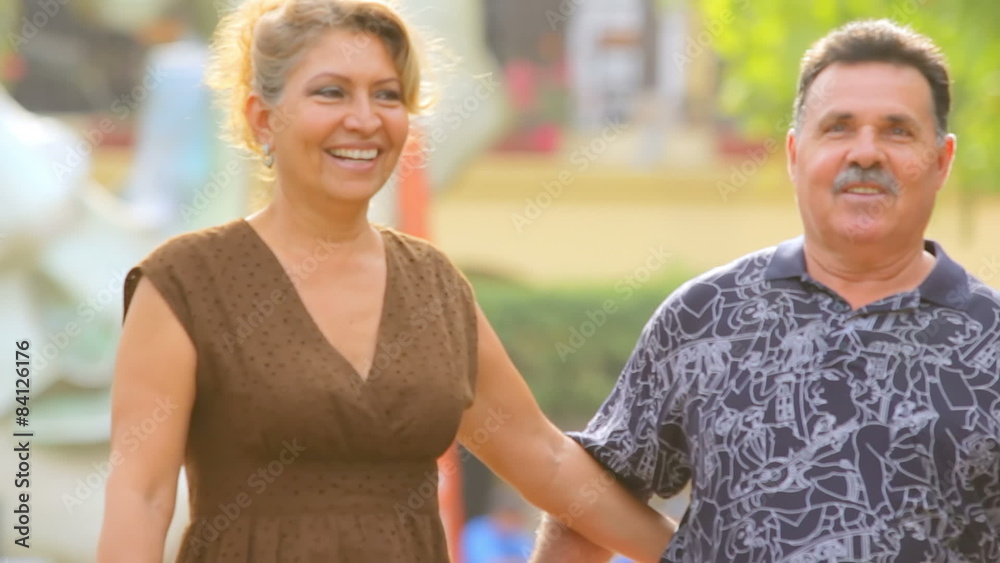 An older couple smile as they walk down the street and kiss An older couple smile as they walk down the street and kiss
