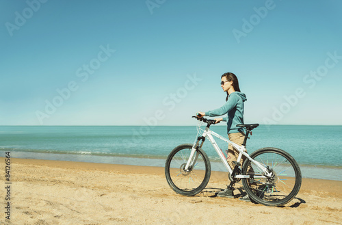 Girl walking with a bicycle on beach