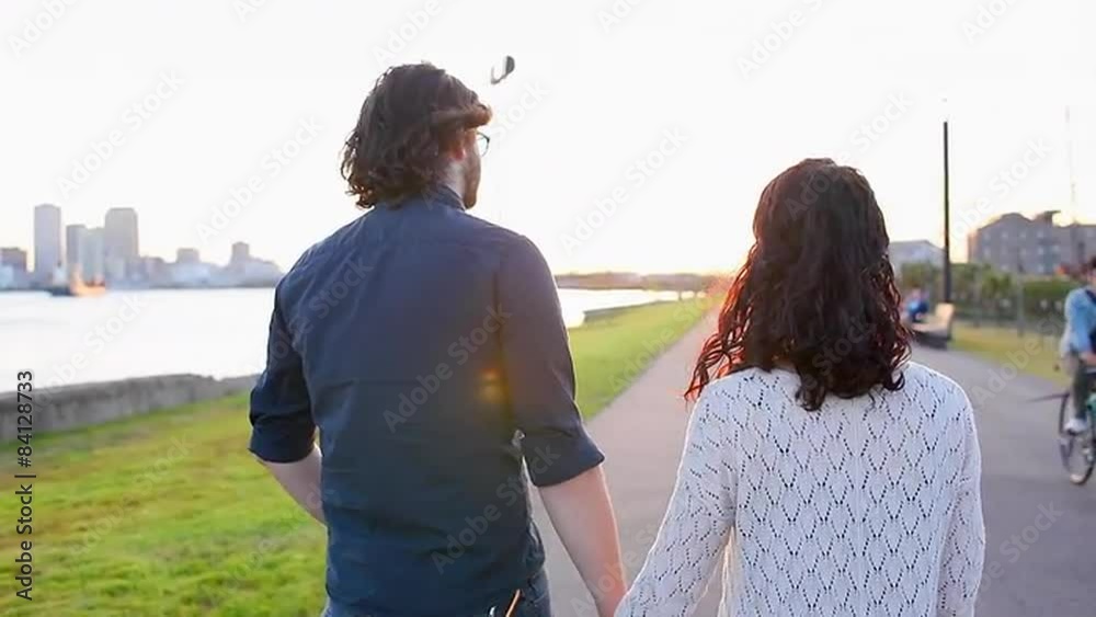Couple walk together in a park near a bay Couple walk together in a park near a bay