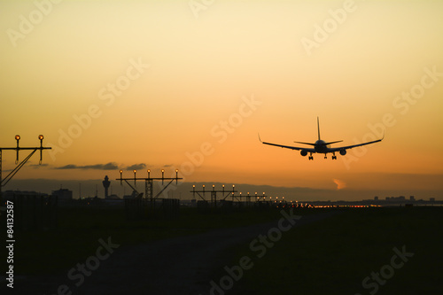 Airplane landing with an orange sky at the background.
