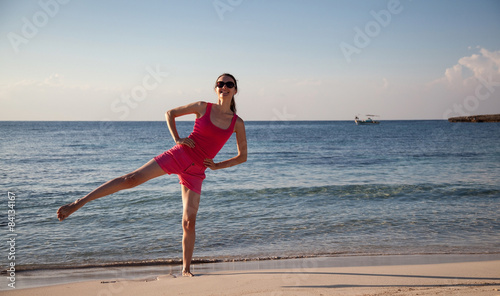 Slender young woman doing exercises on the sea coast