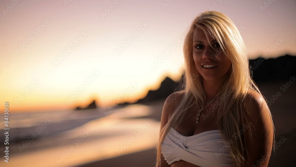 An attractive young woman smiles on the beach at sunset An attractive young woman smiles on the beach at sunset