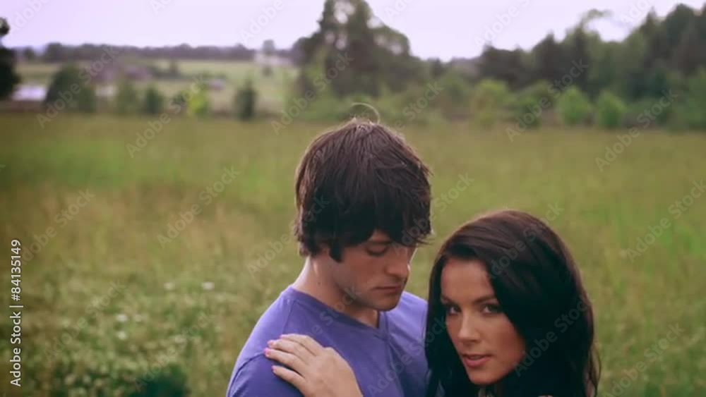a young couple in love embracing each other in a wide open field during the day a young couple in love embracing each other in a wide open field during the day
