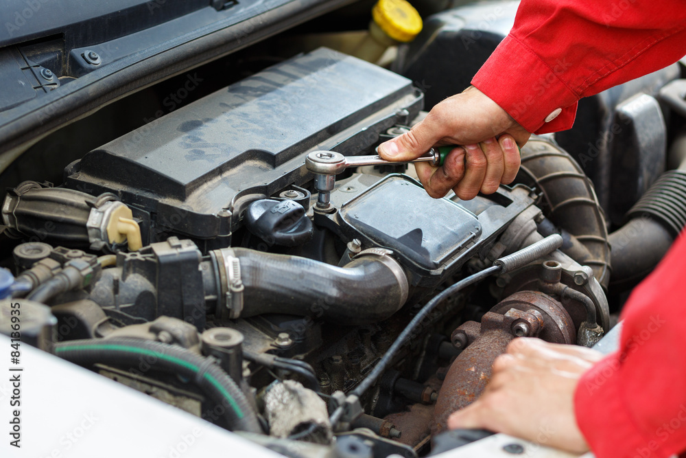 Worker in red overalls working on car car engine Worker in red overalls working on car car engine