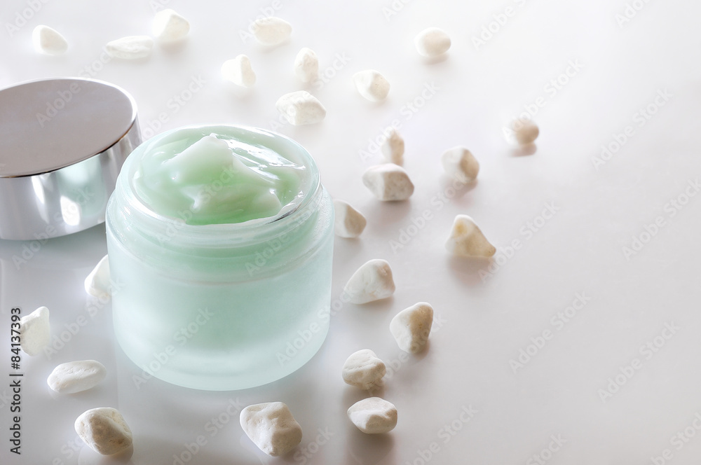 Cream jar open and small white stones isolated Cream jar open and small white stones isolated
