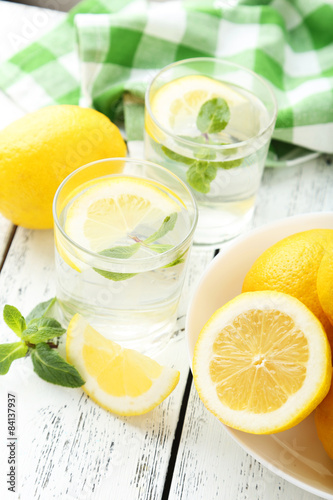 Fresh lemonade with lemon on white wooden background