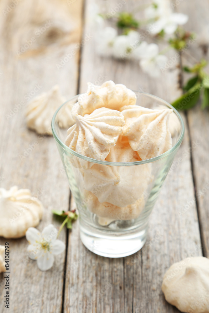 French meringue cookies with glass on grey wooden background