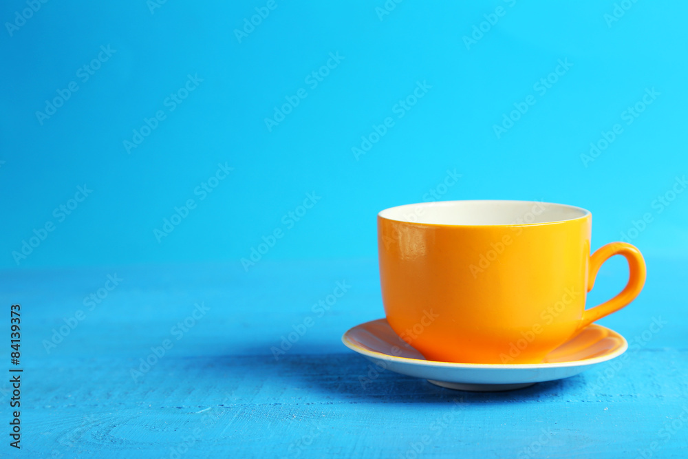 Orange cup on blue wooden background - obrazy, fototapety, plakaty 