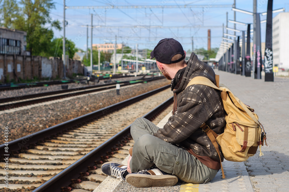 Fototapeta premium Young man waits train on railway station