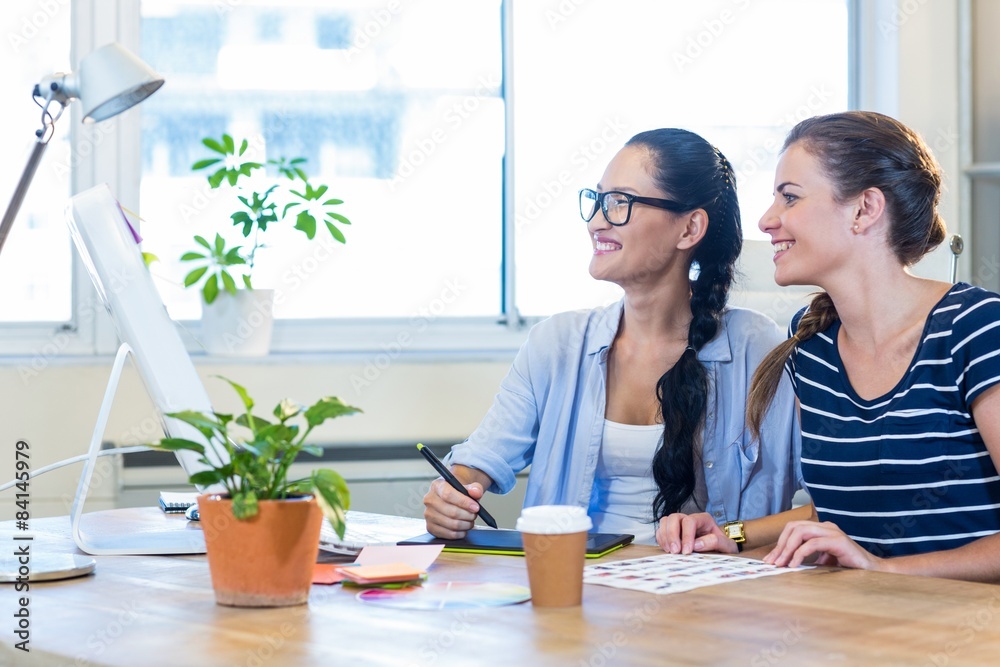 Obraz premium Smiling partners working together on computer and digitizer