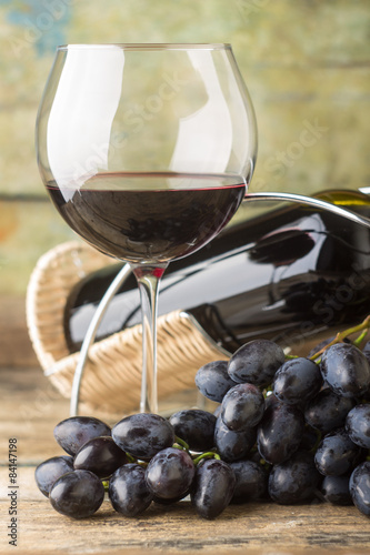 Cluster of fresh dark blue grapes with red wine in glass 