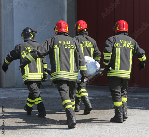 four firemen in action carry a stretcher with injured