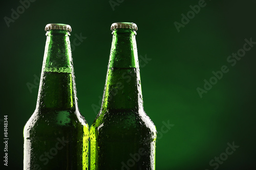 Glass bottles of beer on dark green background