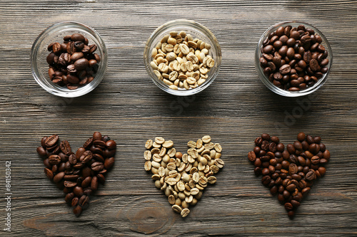 Coffee beans in shape of hearts on wooden background