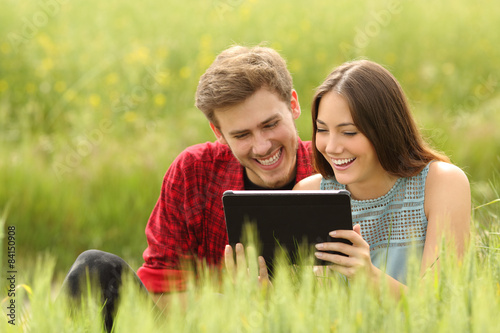 Couple watching videos in a tablet in a field photo