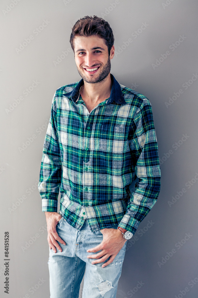 Handsome young man smiling in front of a grey wall Handsome young man smiling in front of a grey wall