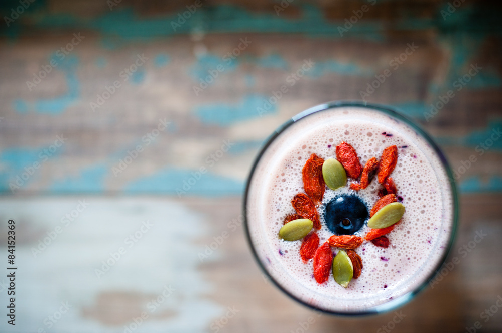 Healthy smoothie made from blended pineapple and kefir yogurt topped with pumpkin seeds, goji berries and a blueberry. Served on a wooden tray, this is a healthy, nutritious breakfast
 - obrazy, fototapety, plakaty 