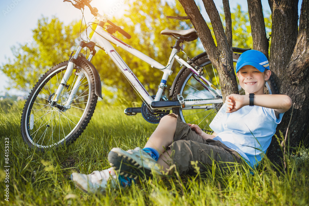 happy kid with a bicycle resting under a tree happy kid with a bicycle resting under a tree