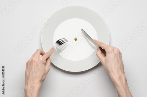hands holding knife and fork on a plate with green peas