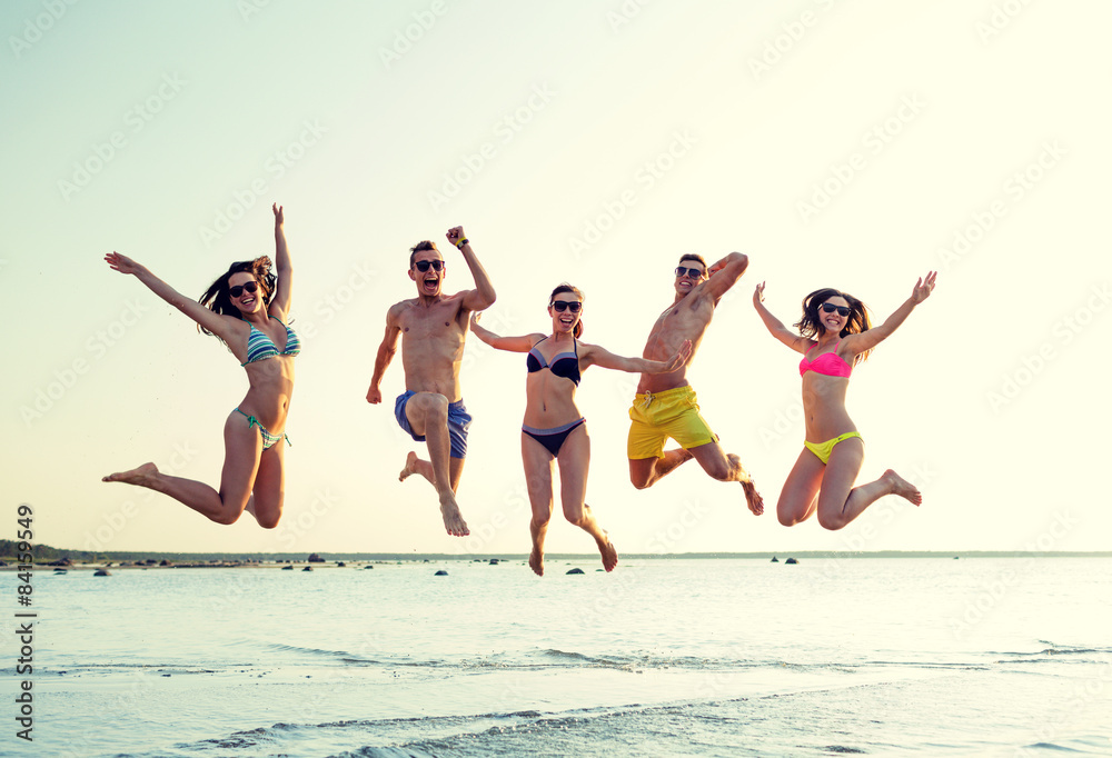 Obraz premium smiling friends in sunglasses on summer beach