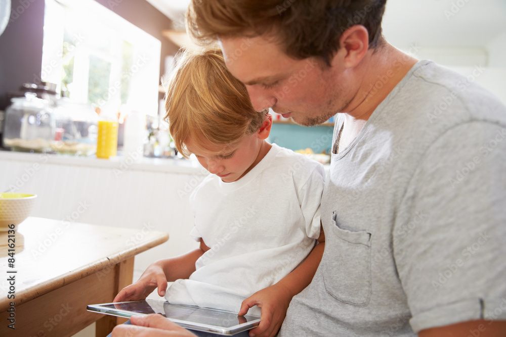 Father And Son Using Digital Tablet At Breakfast Table Father And Son Using Digital Tablet At Breakfast Table