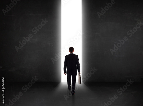 Business person looking at wall with light tunnel opening