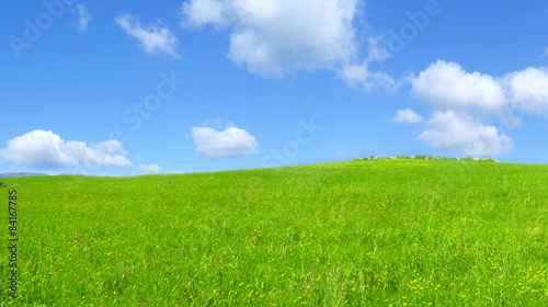 Collina verde all'aperto con nuvole nel cielo blu chiaro © oraziopuccio