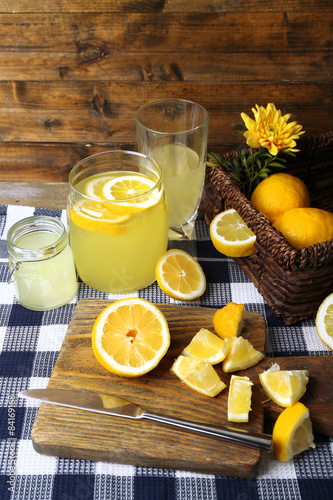 Still life with lemon juice and sliced lemons on wooden background