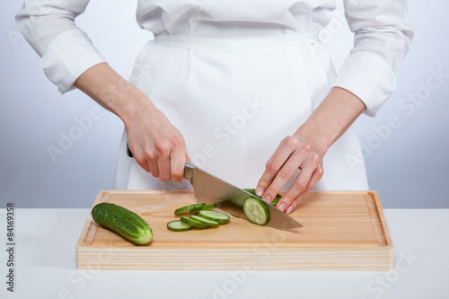 Cook's hands cutting fresh cucumber