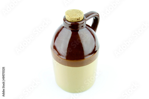 Tableau sur toile Old clay jug with a cork used to hold booze, with a filled glass next to it