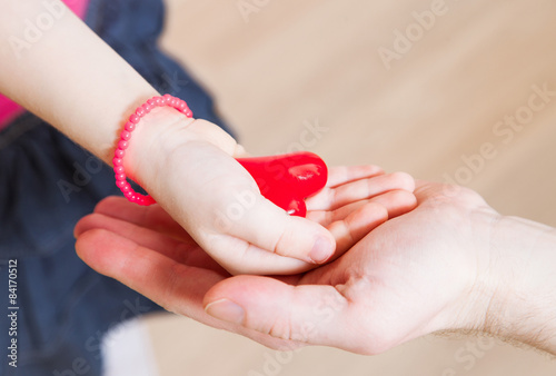 Daughter and her father holding a red heart in their hands