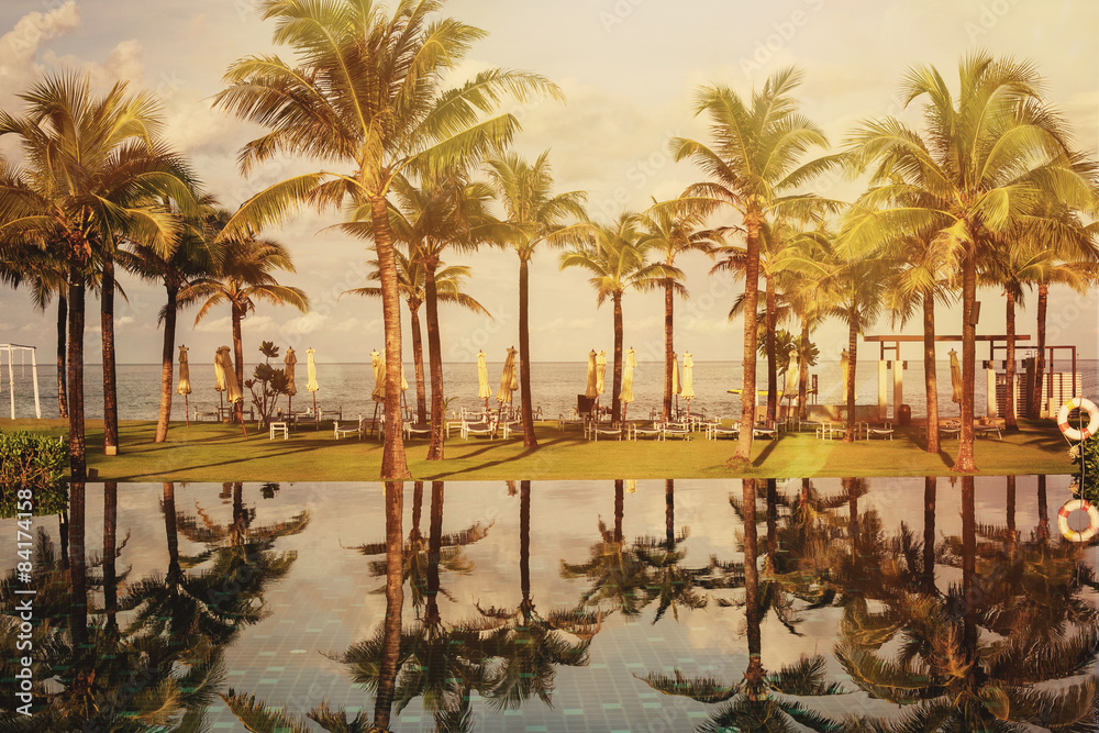 Obraz premium Beautiful palm beach luxury resort with swimming pool in tropics