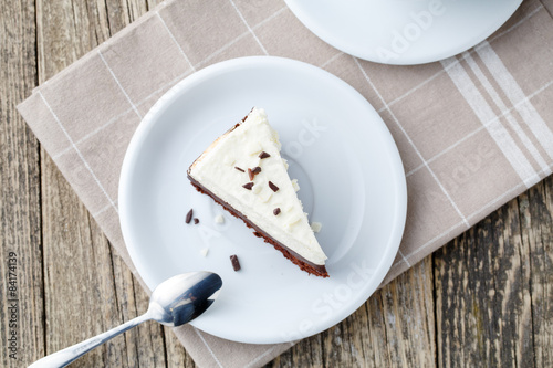 Vanilla cheesecake slice on wooden background.