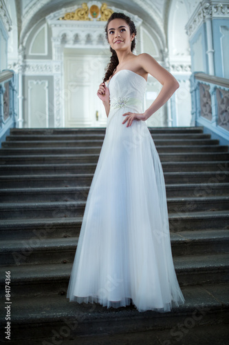 Elegant bride in a white dress standing on the stairs