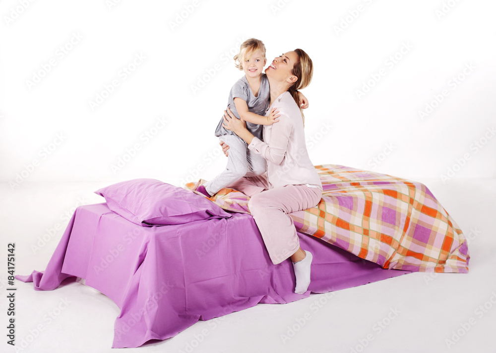 Cute little girl with her mother lying on a bed, 
