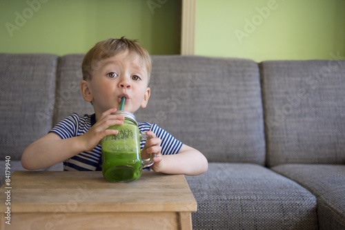 cute child drinking a green smoothie