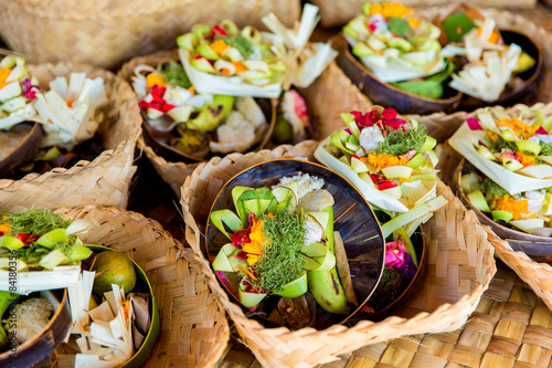 Traditional balinese offerings to gods in Bali with flowers and photo