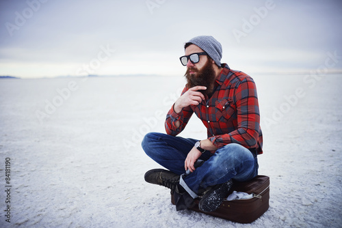 beard lumbersexual hipster sitting on suitcase in deep thought photo