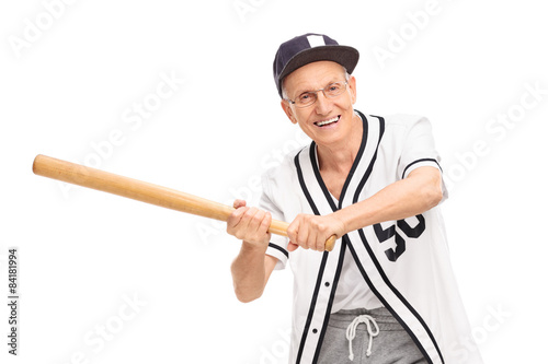 Senior in a baseball jersey swinging a baseball bat and looking