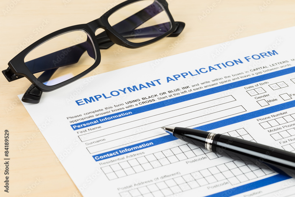 Employment application form with pen and glasses; form is mock-u Employment application form with pen and glasses; form is mock-u