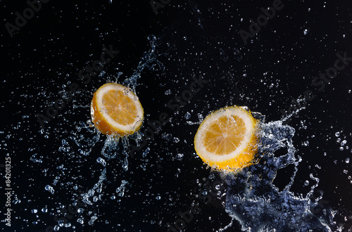 A high-speed shot of a lemon with splashing water, on a black ba