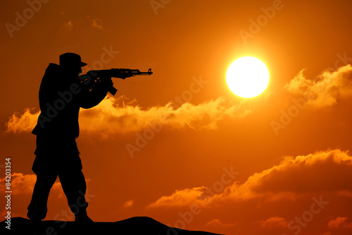 Silhouette shot of soldier holding gun with colorful sky and mou © YURII Seleznov