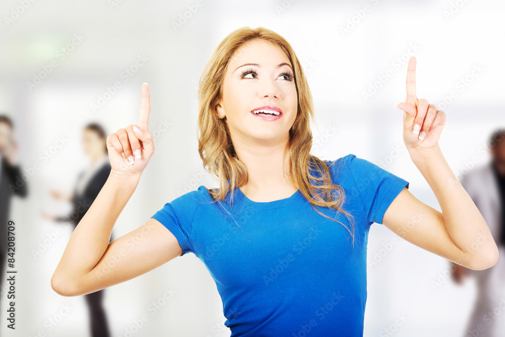 Fototapeta premium Beautiful young woman pointing up.