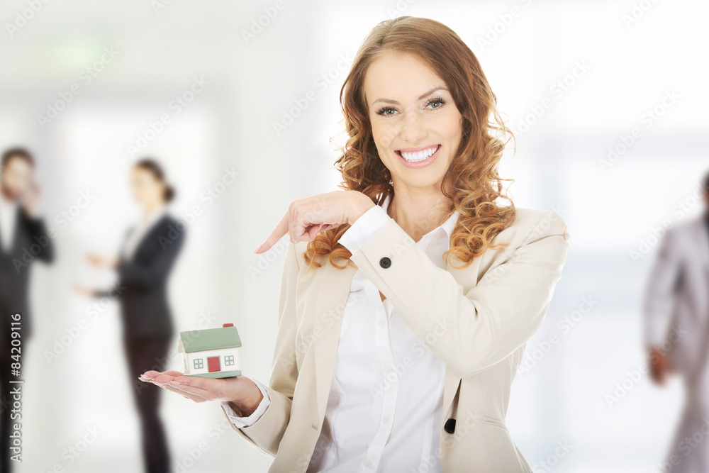Businesswoman pointing on a model house.